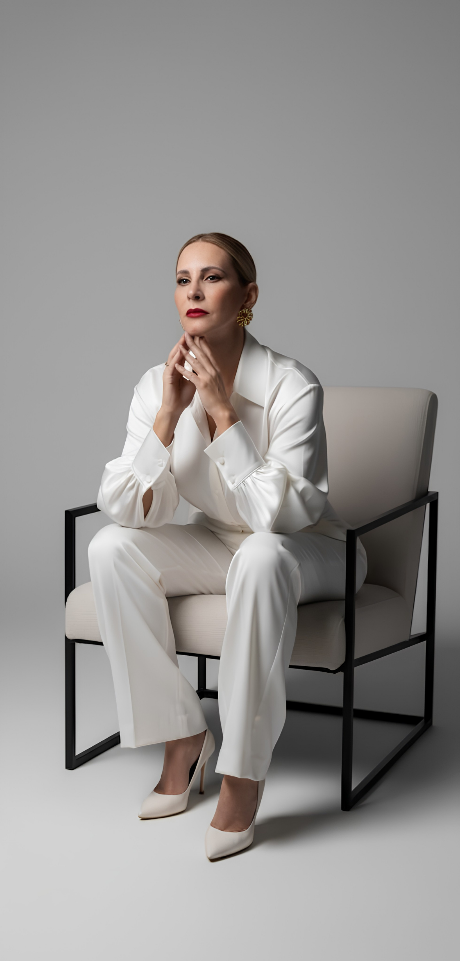 Dra. Giovana Urso sentada, em traje branco, em retrato editorial